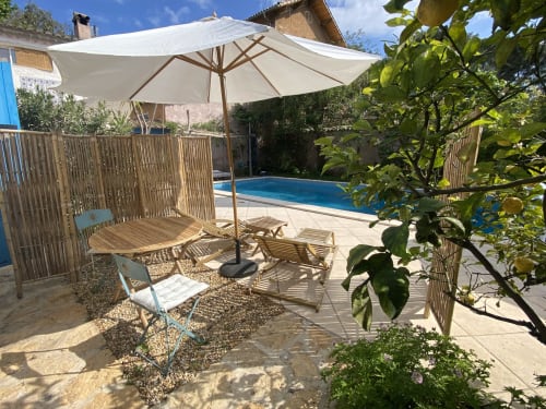 Espace piscine Le Patio aux Oiseaux avec parasol, transats et clôture en bois à La Ciotat