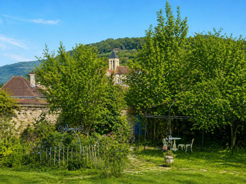 La Villa Malzy garden in Vétheuil with church tower, ivy-covered trellis, and ornate furniture