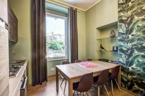 Modern Rome apartment dining area with kitchen, yellow walls, plant wallpaper, and city view window