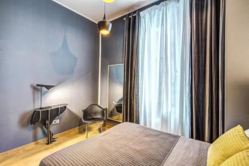 Modern bedroom in Cinque Terre Stylish apartment with blue walls, yellow accents, and large windows with curtains