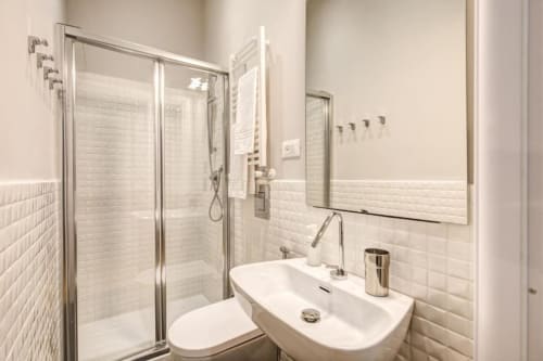 Modern bathroom in Roma apartment with white subway tiles, glass shower enclosure, and sleek fixtures