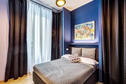 Modern bedroom at Downtown Srl Roma apartment with blue walls, patterned bedding, and wall art