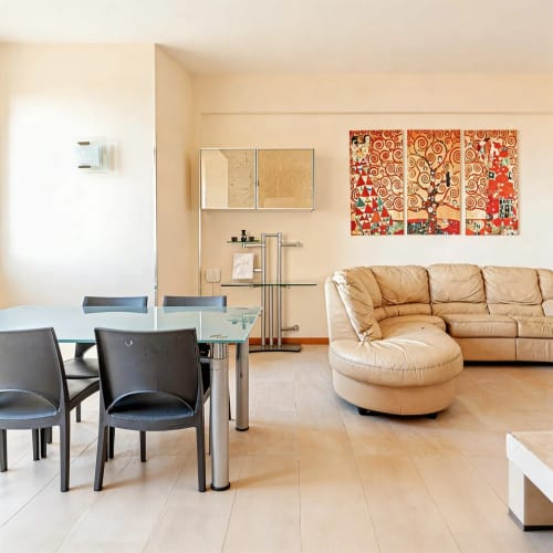 Spacious living room in Roby's Panoramic House apartment, Viterbo, with beige leather sofa, dining area, and modern kitchen
