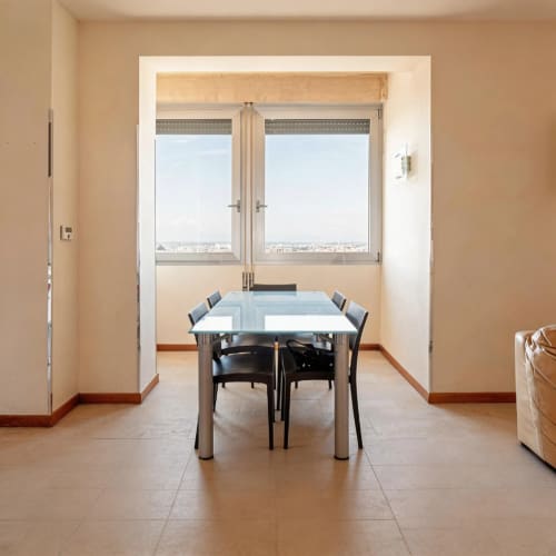Dining area in Roby's Panoramic House Livorno apartment with city views through large windows