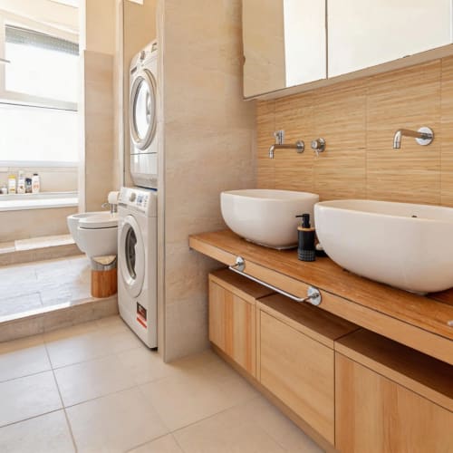 Modern bathroom with dual vessel sinks, wood vanity, stacked washer-dryer at Roby's Panoramic House in Livorno