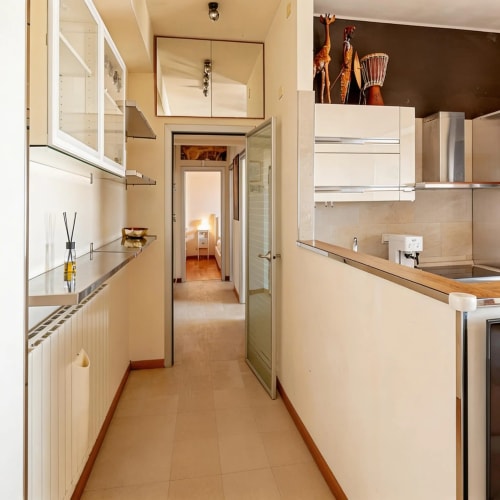 Modern galley kitchen in Roby's Panoramic House apartment, Livorno, with white cabinetry and terracotta flooring