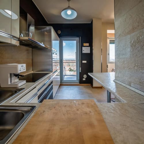 Modern kitchen in Roby's Panoramic House apartment in Livorno with stainless steel appliances, city views through balcony