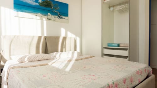 Bright bedroom with queen bed, floral bedding, and ocean view at Versilia Panoramic Luxury in Como, Italy