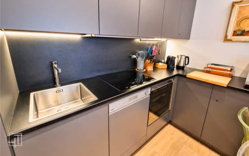 Modern kitchen in Padova apartment with stainless steel sink, black countertop, induction cooktop, and built-in oven