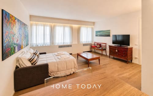 Spacious studio apartment in Padova with bed, sofa, wooden furniture, TV, and city views - Hometoday