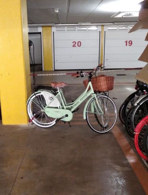 Light green vintage bicycle with brown basket parked in underground garage at Versilia Panoramic Luxury hotel in Como, Italy