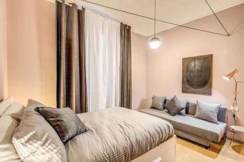 Modern bedroom in Cinque Terre New Liberty apartment, Rome with bed, sofa, pendant light, and neutral décor