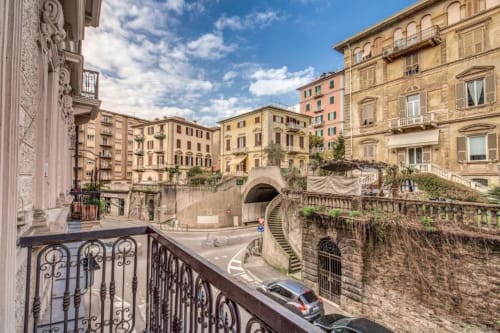 Historic Roman apartment balcony overlooking cobblestone street with classical architecture and ivy-covered stone walls