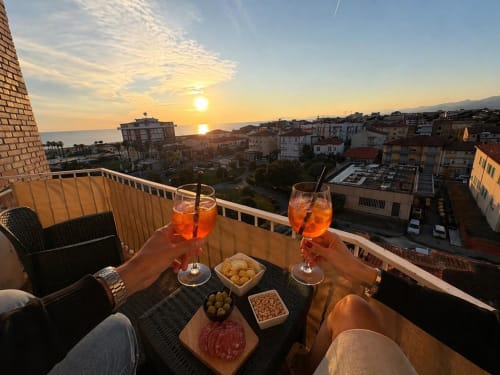 Sunset aperitivo on luxury balcony in Como, Italy with sea and mountain views, cocktails and appetizers