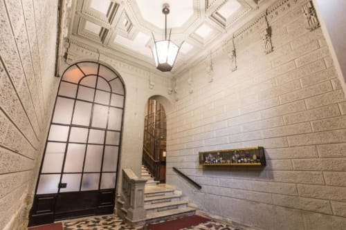 Elegant staircase entry of Rome apartment with Art Deco ceiling, arched window, and brick walls