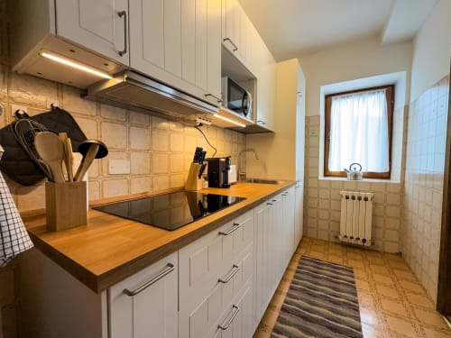 Cucina moderna nell'appartamento Casa Dolomia ad Auronzo di Cadore, con mobili bianchi e piano di lavoro in legno