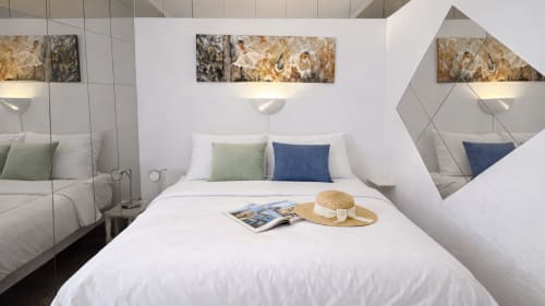 Dormitorio moderno en Holidays Costa Brava con vista al mar, cama blanca, almohadas decorativas, espejo y sombrero de paja