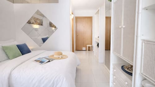 Moderno dormitorio con vista al mar en Holidays Costa Brava, Empuriabrava, con ropa de cama blanca, espejos decorativos y acceso a