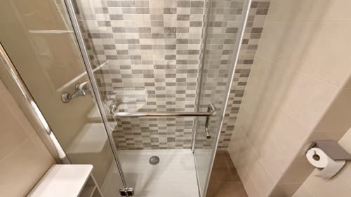 Moderno baño con cabina de ducha y azulejos de cuadros en el techo del apartamento Holidays Costa Brava en Empuriabrava, España
