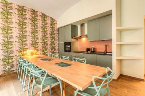 Cucina e zona pranzo moderne nell'appartamento Croce di Malta Royale a Roma, con sedie verde menta, tavolo in legno