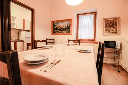 Sala da pranzo dell'appartamento Casa Dolomia ad Auronzo di Cadore, con tavolo preparato, sedie in legno e vista sulle montagne