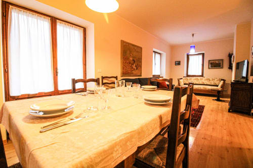 Ampia sala da pranzo nell'appartamento Casa Dolomia ad Auronzo di Cadore, con tavolo apparecchiato, sedie in legno e vista sulle montagne