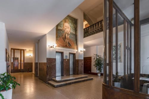 Elegante ingresso della hall di Downtown Srl a Roma con pavimenti in marmo, opere d'arte classica e ringhiere ornamentali