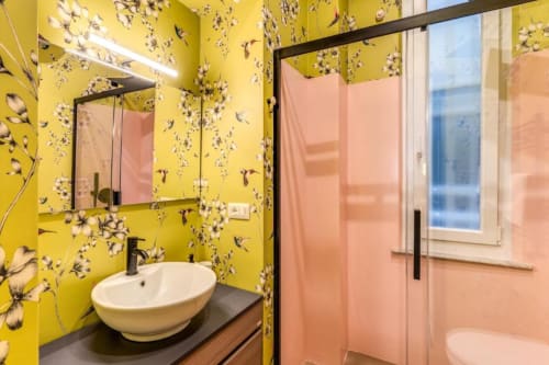 Lussuoso bagno nell'appartamento Croce di Malta Royale, Roma con carta da parati a fiori gialli, lavabo bianco moderno, specchio nero e