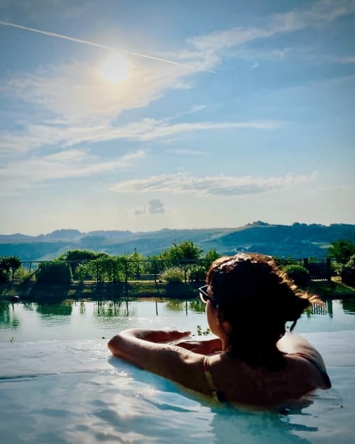 Guest relaxing in thermal pool overlooking Tuscan hills at Agriturismo CasaViva, Pozzo della Chiana