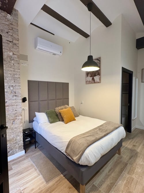Dormitorio moderno en Be Gonfre Flats, Valencia, con cama queen, ladrillo visto, iluminación colgante y mobiliario contemporáneo