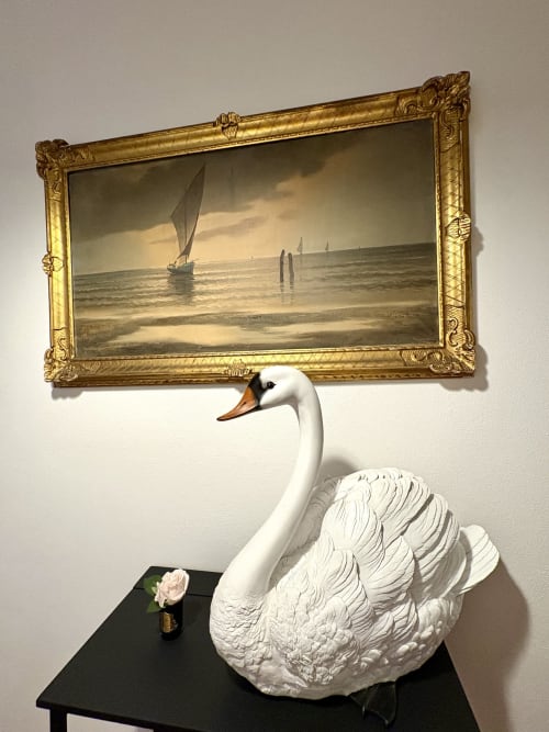 Scultura di cigno bianco con becco arancione sotto dipinto dorato di paesaggio marino a La Dolce Casa, Cremia Italia