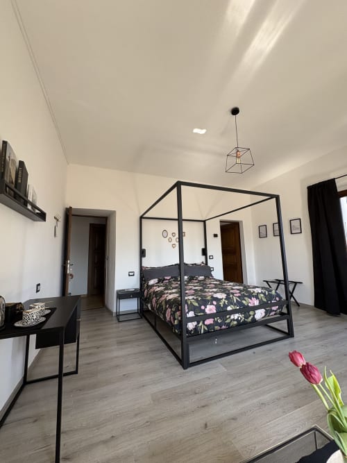 Camera da letto moderna con letto a baldacchino nero e biancheria floreale presso La Dolce Casa B&B a Cremia, Italia