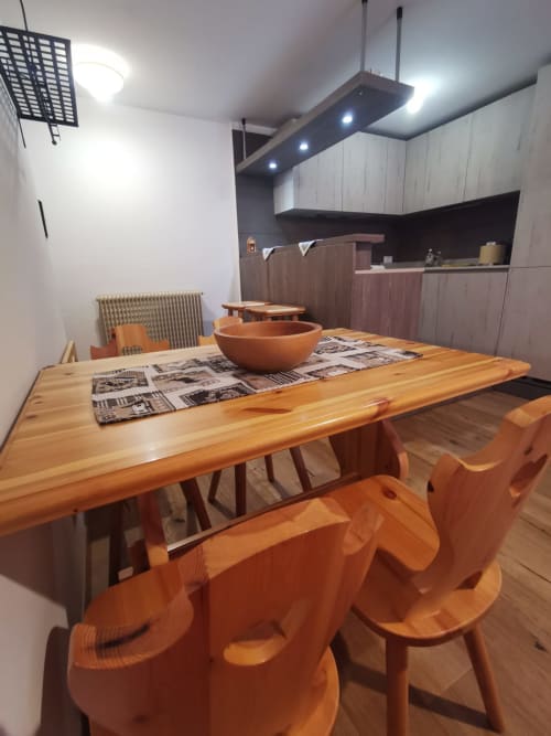 Moderna zona pranzo nell'appartamento Lavaredo, Auronzo di Cadore, con tavolo in legno, sedie arancioni e cucina attrezzata