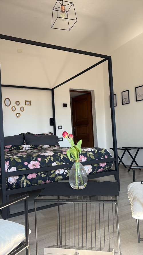 Camera La Dolce della B&B La Dolce Casa a Cremia con letto a quattro colonne nero, biancheria floreale e tulipani rosa