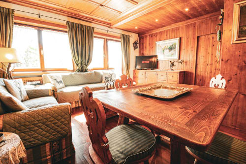 Accogliente zona living con rivestimenti in legno a Cortina d'Ampezzo, tavolo da pranzo, divano, vista montagna e TV moderna
