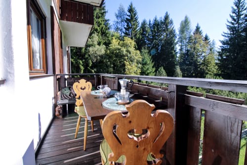 Terrazza in legno con sedie intagliate con vista sulla foresta alpina dell'appartamento Cortina Wood Home, Auronzo di Cadore