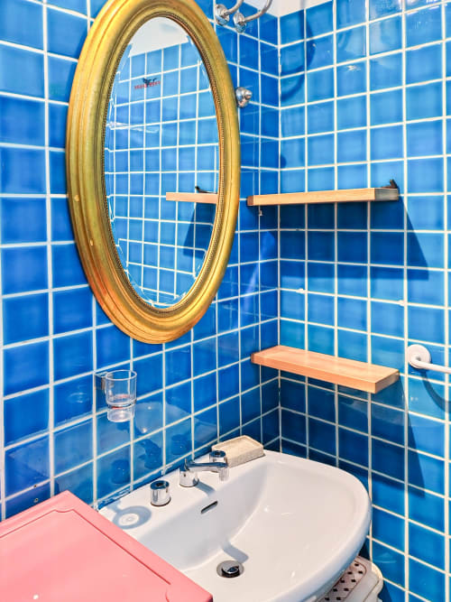 Vibrant blue tiled bathroom at Vesta Home Rent Padova with gold oval mirror and modern white sink