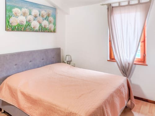 Bright bedroom at Vesta Home Rent in Padova with gray headboard, peach bedding, sea view window, and floral wall art