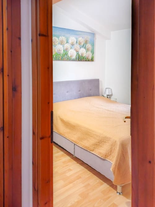 Cozy bedroom at Vesta Home Rent in Padova with yellow bedding, gray headboard, and white walls featuring dandelion artwork