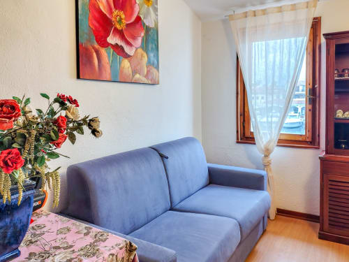 Bright apartment living room at Vesta Home Rent, Padova with blue sofa, red flowers, sea view window, and wooden furniture.