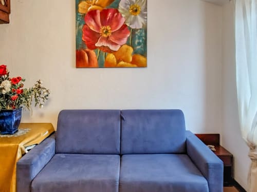 Blue sofa in Dolce Sardinia apartment at Vesta Home Rent, Padova, with colorful flower artwork above