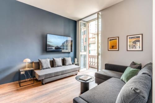 Modern Roma apartment living room with dual sofas, wall-mounted TV, city balcony view, and contemporary décor