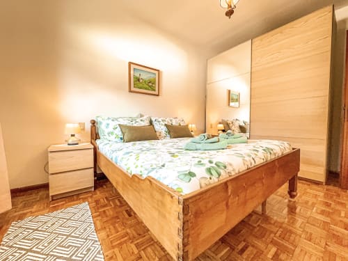 Ampia camera da letto nell'appartamento Rugiada ad Auronzo di Cadore, con letto in legno, armadio a specchio e vista sulle montagne