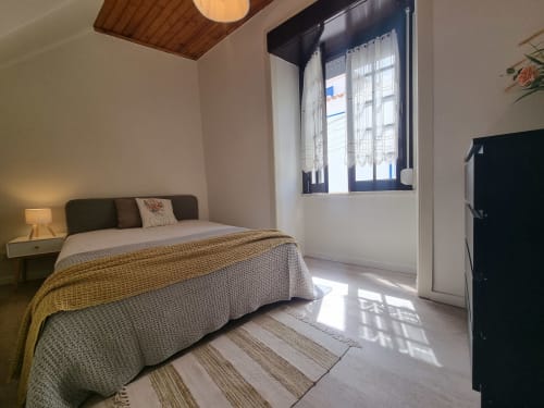 Bright bedroom at Ericeira Property with bed, wooden ceiling, large window, and minimalist decor