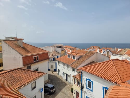 Ericeira Property rooftop view with terracotta tiles, white buildings, and ocean horizon in Portugal