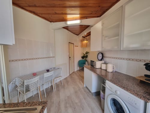 Modern kitchen and dining area at Ericeira Property with granite counters, white cabinetry, wooden ceiling, and checkered