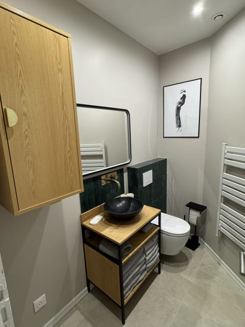 Modern bathroom at Cosy cottage By Alice with black sink, wooden vanity, white toilet, and mirror in Bouc Bel Air