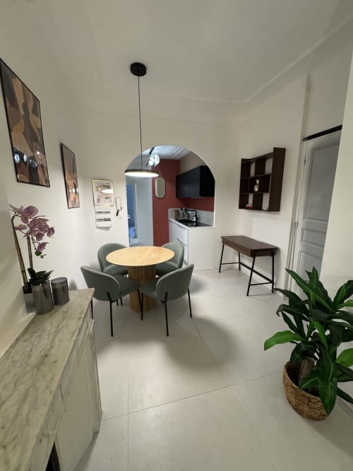 Modern open-plan studio at Cosy Cottage By Alice featuring round wooden dining table with green chairs, kitchenette, and