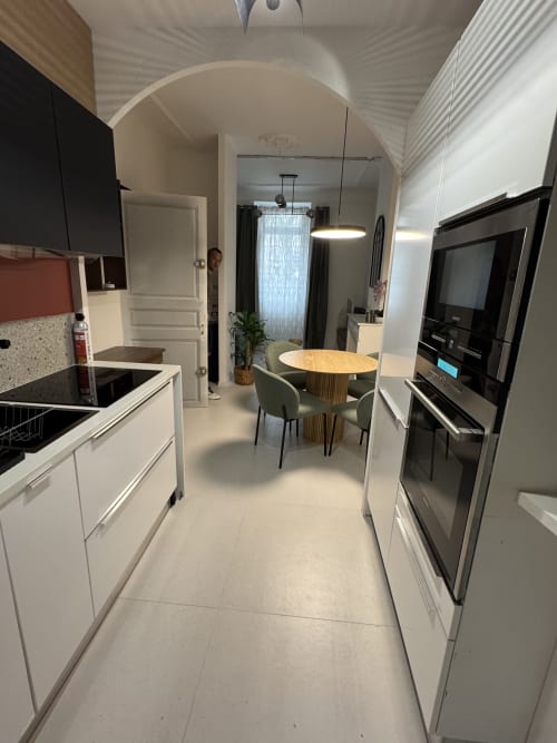 Modern kitchen-dining area at Cosy cottage By Alice, Bouc Bel Air, with white cabinetry, black appliances, wooden table, and