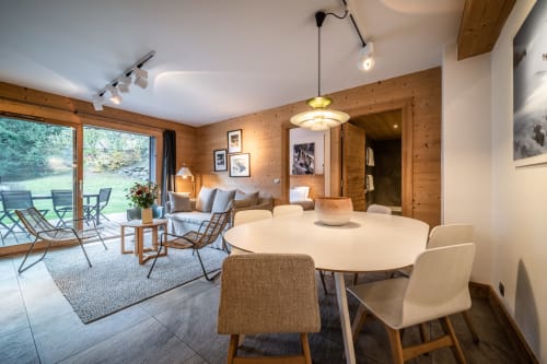 Modern wood-paneled apartment with round dining table, living area, and mountain views at Le Chalet Mont-Blanc, Les Houches